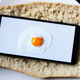 split baguette with cell phone on it displaying egg